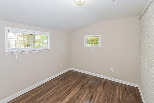 spare room featuring lofted ceiling, dark hardwood / wood-style flooring, and plenty of natural light