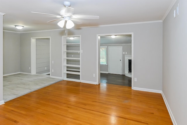 unfurnished room featuring a brick fireplace, crown molding, light hardwood / wood-style floors, and ceiling fan