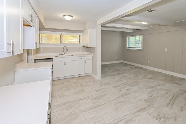 kitchen with wooden walls, beam ceiling, sink, and white cabinets