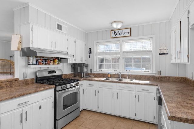 kitchen featuring sink, light tile patterned floors, appliances with stainless steel finishes, white cabinetry, and extractor fan