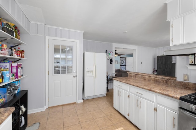 kitchen featuring stainless steel electric stove, white cabinetry, white refrigerator with ice dispenser, light tile patterned floors, and ceiling fan