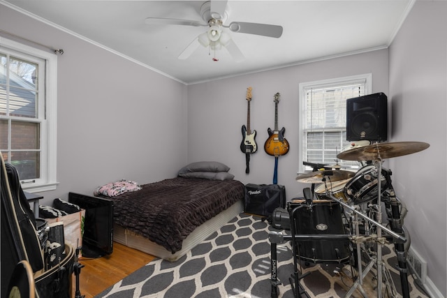 bedroom with crown molding, ceiling fan, and hardwood / wood-style floors