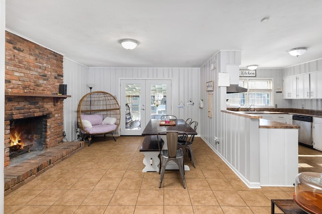 dining room with a brick fireplace, light tile patterned floors, and french doors