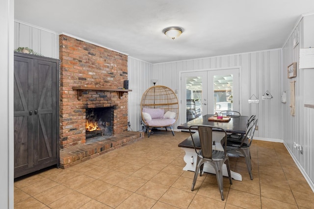 dining room featuring ornamental molding, light tile patterned floors, a fireplace, and french doors