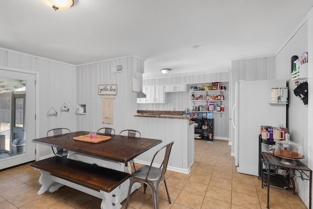 dining area featuring wooden walls and light tile patterned flooring