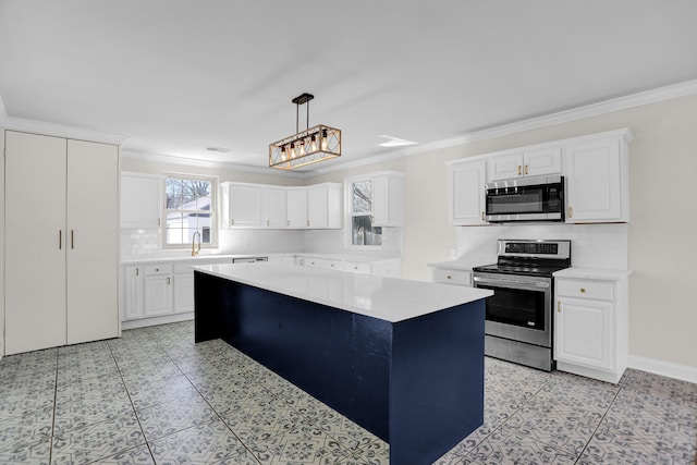 kitchen featuring decorative light fixtures, a center island, ornamental molding, appliances with stainless steel finishes, and white cabinets