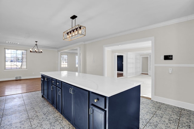 kitchen featuring crown molding, blue cabinetry, and decorative light fixtures