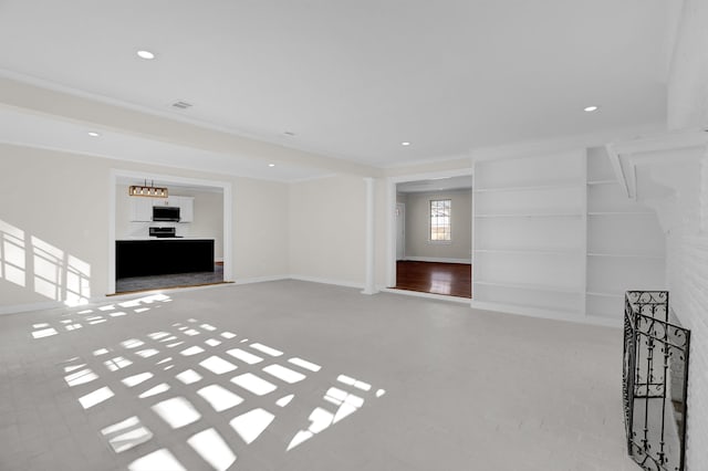 unfurnished living room featuring built in shelves and ornamental molding