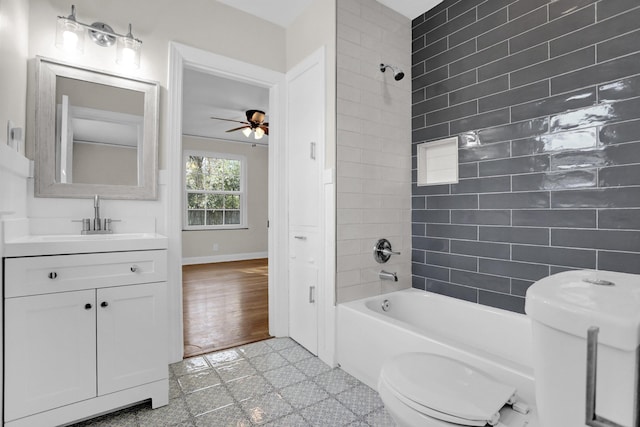 full bathroom with tiled shower / bath, vanity, ceiling fan, and toilet