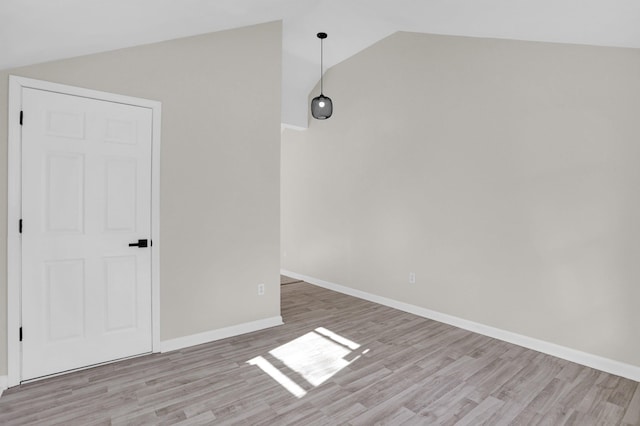 spare room featuring vaulted ceiling and light hardwood / wood-style floors