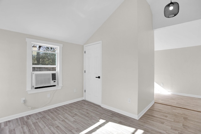 empty room with cooling unit, lofted ceiling, and light wood-type flooring