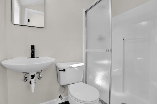 bathroom featuring sink, toilet, and a shower with door