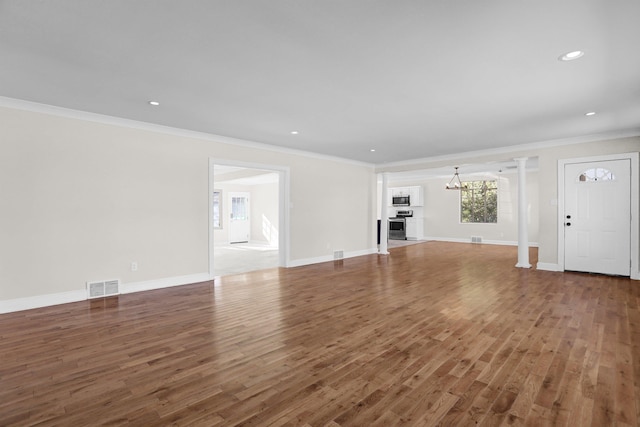 unfurnished living room with a notable chandelier, dark wood-type flooring, ornamental molding, and decorative columns