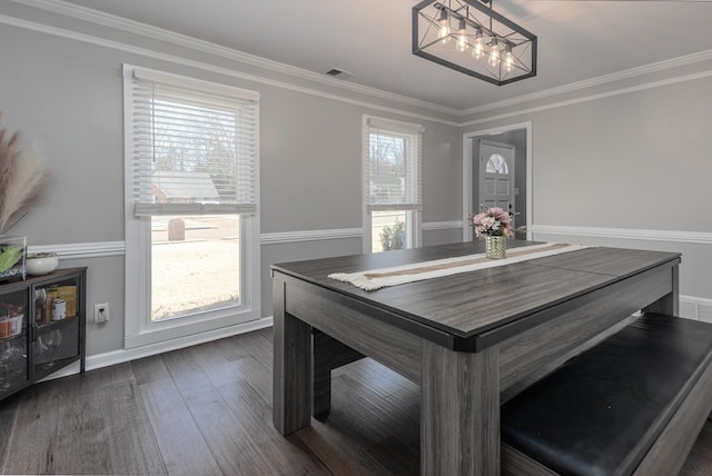 dining room featuring crown molding, dark wood-type flooring, an inviting chandelier, and a healthy amount of sunlight