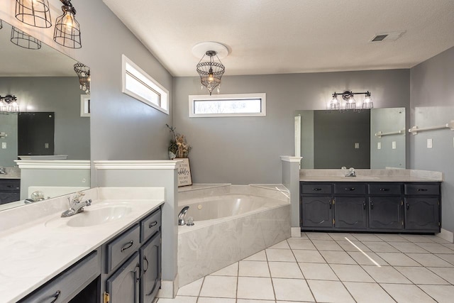 bathroom featuring vanity, tile patterned flooring, a textured ceiling, and a bathtub