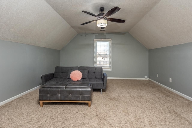 interior space with ceiling fan, vaulted ceiling, light colored carpet, and a textured ceiling