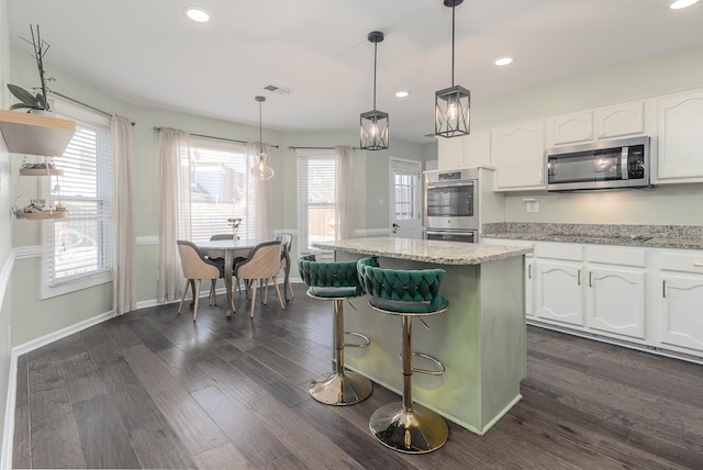 kitchen with pendant lighting, a center island, white cabinets, and appliances with stainless steel finishes