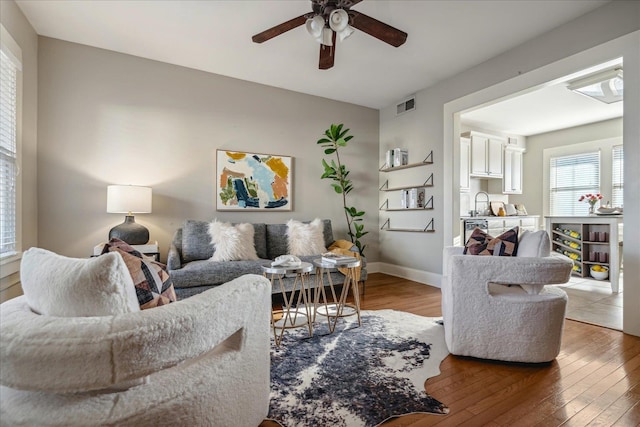 living room featuring wood-type flooring, sink, and ceiling fan