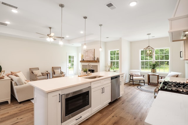 kitchen featuring white cabinetry, black microwave, dishwasher, sink, and a kitchen island with sink