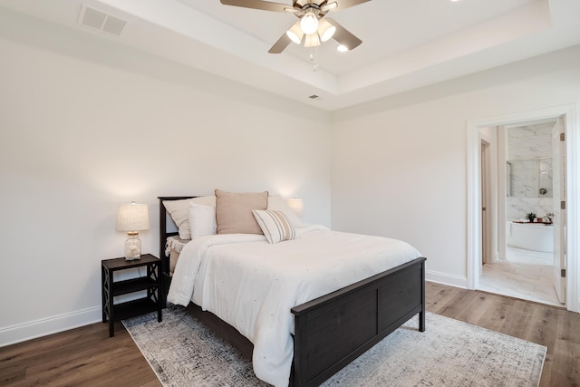 bedroom with a raised ceiling, hardwood / wood-style floors, and ceiling fan