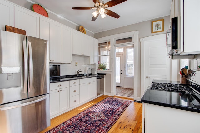 kitchen with white cabinets, decorative backsplash, ceiling fan, stainless steel appliances, and light hardwood / wood-style flooring