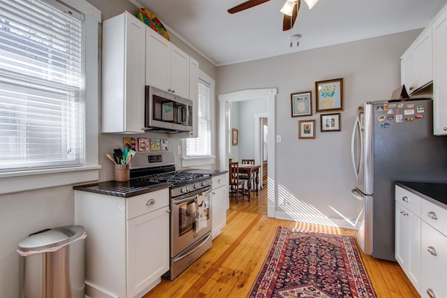 kitchen with appliances with stainless steel finishes, a wealth of natural light, light hardwood / wood-style floors, and white cabinets