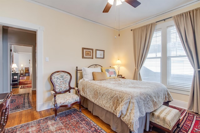 bedroom with ornamental molding, wood-type flooring, and ceiling fan