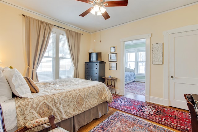 bedroom featuring ceiling fan, ornamental molding, hardwood / wood-style floors, and multiple windows