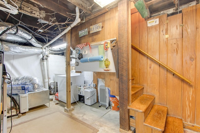 basement featuring washing machine and clothes dryer and wood walls