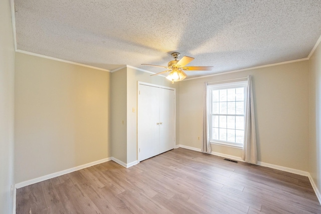 unfurnished bedroom featuring crown molding, light hardwood / wood-style flooring, ceiling fan, a textured ceiling, and a closet