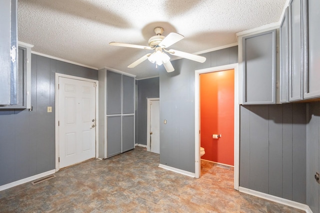 interior space featuring crown molding, gray cabinets, a textured ceiling, and ceiling fan