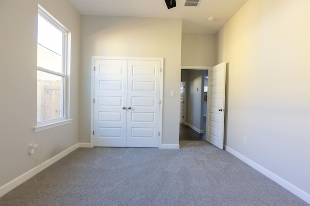 unfurnished bedroom featuring carpet floors, multiple windows, and a closet