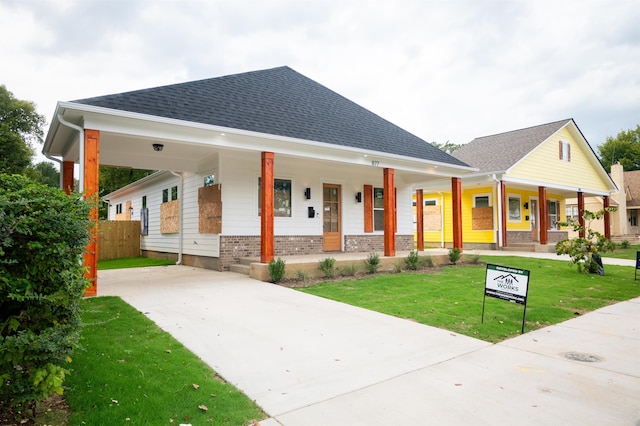 view of front of property featuring a front lawn, a carport, and a porch