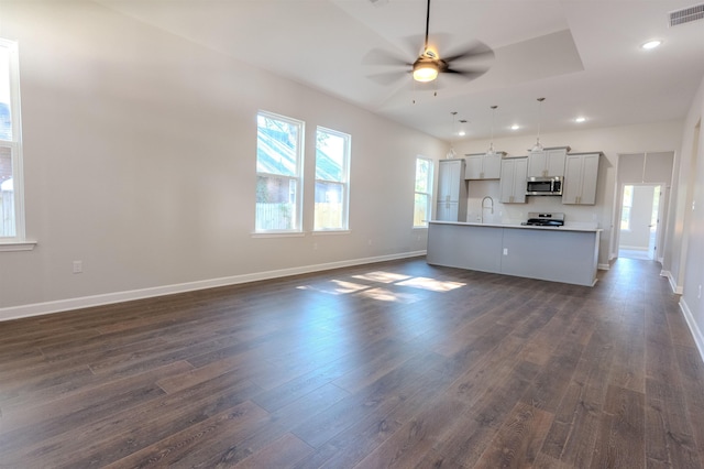 kitchen with a center island with sink, hanging light fixtures, stainless steel appliances, ceiling fan, and dark hardwood / wood-style floors