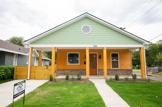 bungalow-style home featuring covered porch and a front lawn