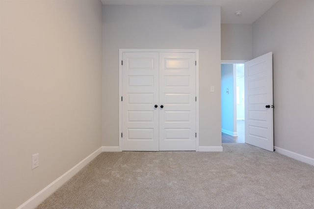 unfurnished bedroom with a closet and light colored carpet