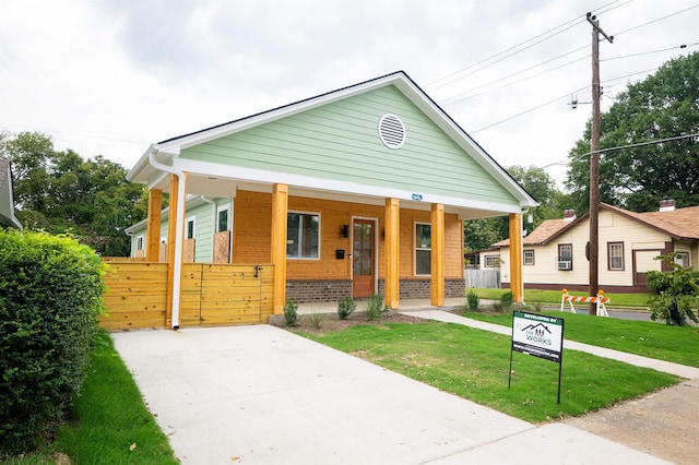 bungalow-style home featuring covered porch and a front yard