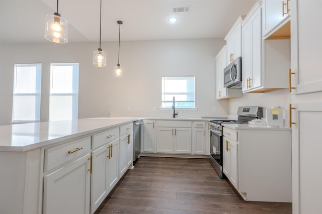 kitchen featuring appliances with stainless steel finishes, decorative light fixtures, sink, and white cabinets