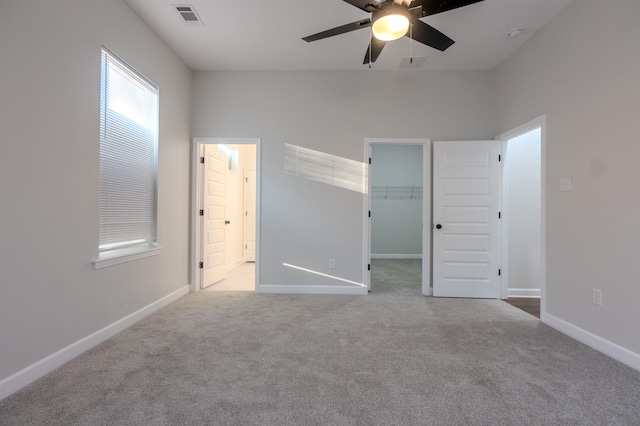 unfurnished bedroom featuring a closet, a spacious closet, ceiling fan, connected bathroom, and light carpet