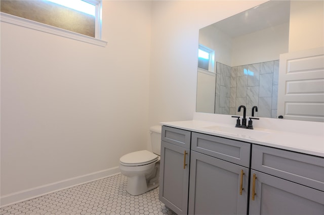 bathroom featuring a tile shower, vanity, and toilet