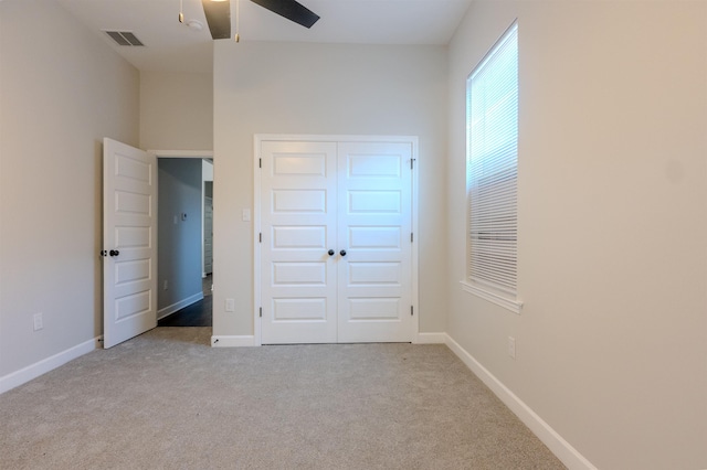 unfurnished bedroom featuring ceiling fan, light carpet, and a closet