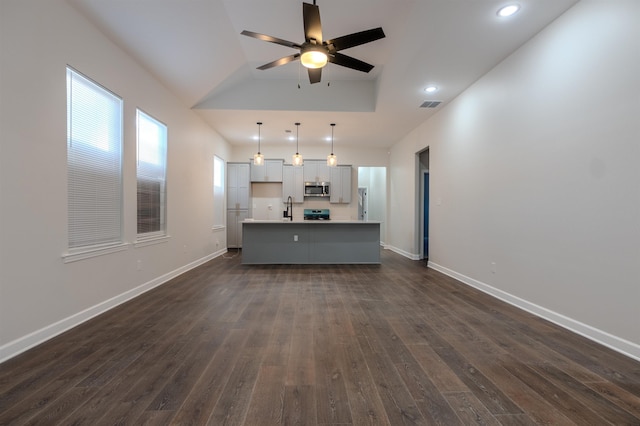 kitchen featuring decorative light fixtures, dark wood-type flooring, an island with sink, and plenty of natural light