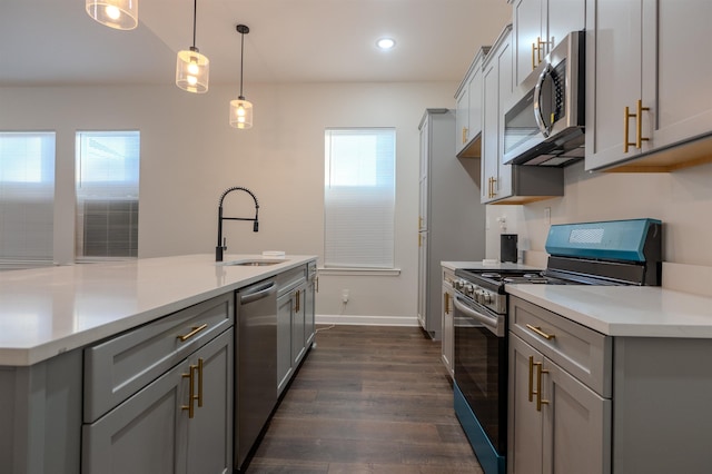 kitchen featuring appliances with stainless steel finishes, a center island with sink, gray cabinetry, pendant lighting, and sink