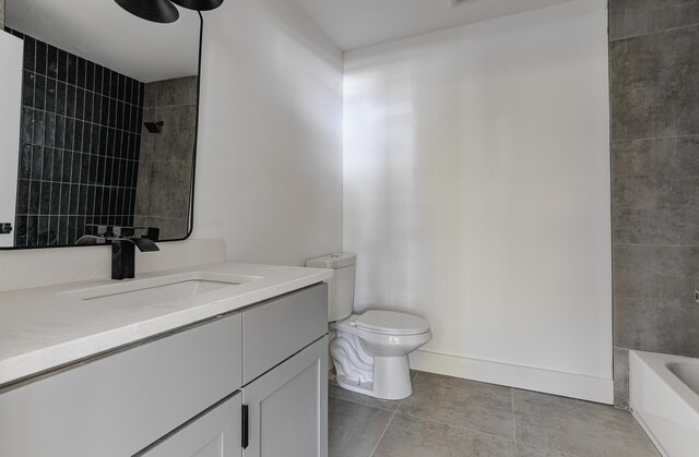 bathroom featuring tile patterned flooring, toilet, vanity, tub / shower combination, and baseboards
