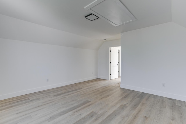 additional living space with attic access, vaulted ceiling, baseboards, and light wood-style flooring