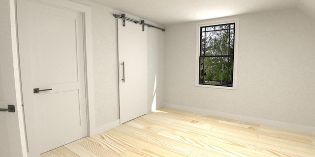 unfurnished bedroom with a barn door, a closet, and light hardwood / wood-style flooring