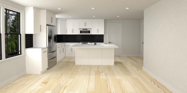 kitchen featuring stainless steel refrigerator with ice dispenser, sink, backsplash, an island with sink, and white cabinets