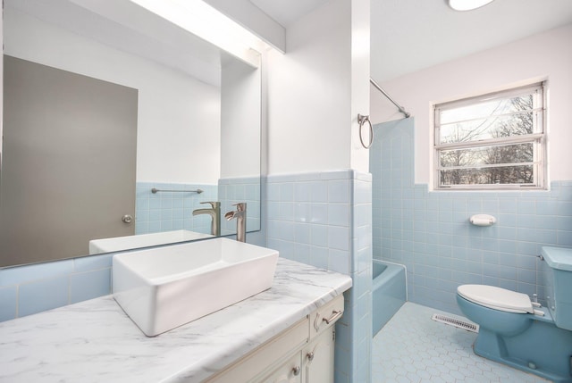 full bathroom with tile walls, vanity, bathtub / shower combination, tile patterned floors, and toilet