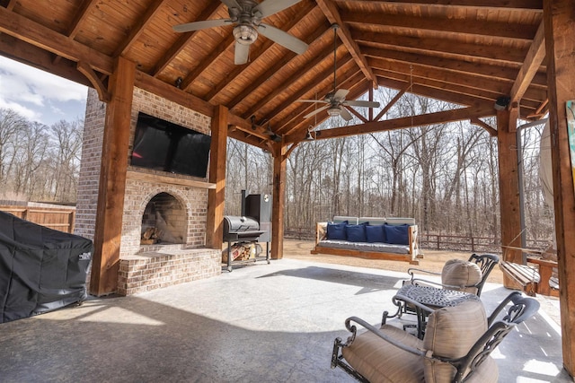 view of patio featuring an outdoor brick fireplace, ceiling fan, grilling area, and a gazebo