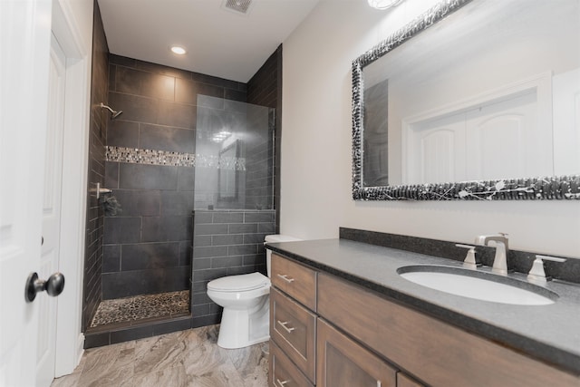 bathroom featuring vanity, toilet, and a tile shower